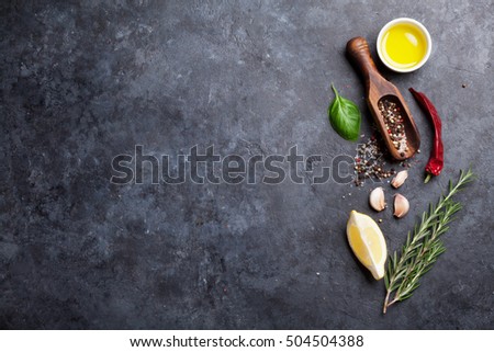Herbs and spices. Cooking ingredients. Rosemary, basil, olive oil, salt and pepper. Top view over stone table with copy space for your recipe