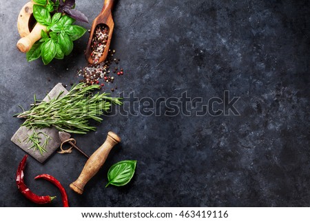 Herbs and spices cooking on stone table. Basil, rosemary, pepper and salt. Top view with copyspace