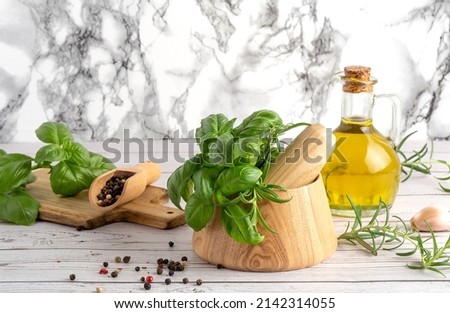 Herbs and Spices, Mortar and Pestle, wooden board, rosemary and basil, oil and pepper and salt on a wooden spoon