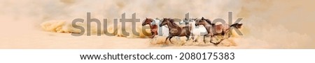 A herd of galloping horses in a cloud of dust