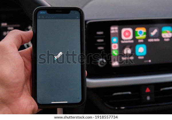Here\
app on the screen of smart phone in mans hand on the background of\
car dashboard screen with application of navigation or maps from\
Apple Car play. January 2021, Prague, Czech\
Republic