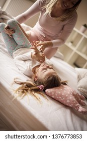 Here Comes The Tickle Monster. Mother Daughter Playing In Bed.