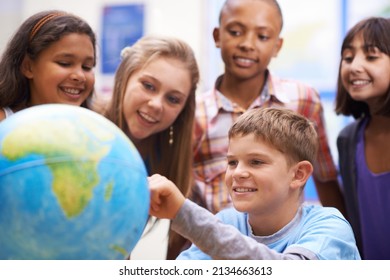 Here it is - Geography class. A group of pupils looking at a globe during geography class. - Powered by Shutterstock