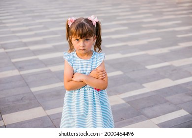 Here Is A Little Girl Standing In A Public Park. The Child Is Offended And Upset. Pampering And Disobedience. Parenting.