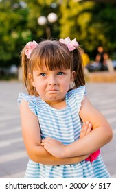 Here Is A Little Girl Standing In A Public Park. The Child Is Offended And Upset. Pampering And Disobedience. Parenting.