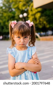 Here Is A Little Girl Standing In A Public Park. The Child Is Offended And Upset. Pampering And Disobedience. Parenting.