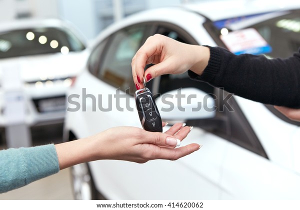 Here you go. Horizontal cropped hot\
of a car dealer passing keys to a new car female\
owner