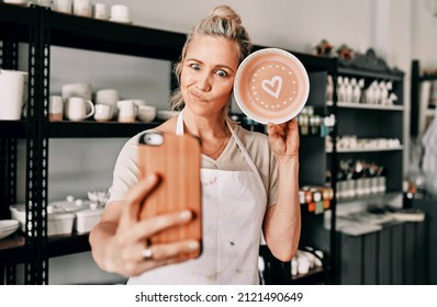 Here's the final look. Cropped shot of an attractive mature woman using her cellphone to take a selfie with her pottery in her studio. - Powered by Shutterstock
