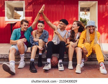 Here's to friendship. Group of multiethnic young people enjoying hanging out together outdoors in the city. Cheerful generation z friends having fun and making happy memories. - Shutterstock ID 2133430029