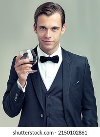 Heres to frivolity. A portrait of a dapper young man with a glass of wine wearing a vintage suit.