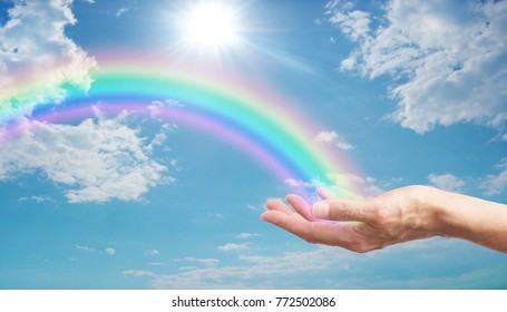 Here's a Rainbow  for You - female hand with a bright rainbow arcing across a blue sky with fluffy clouds and a bright sun burst
 - Powered by Shutterstock