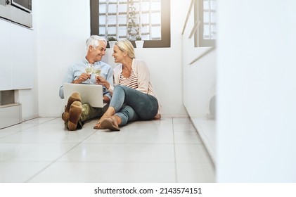 Heres To Us, Babe. Full Length Shot Of An Affectionate Mature Couple Drinking Wine While Browsing The Web On Their Kitchen Floor.