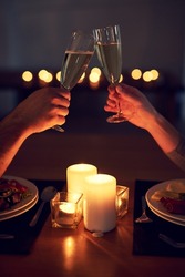 Heres To Us And Our Future. Cropped Shot Of An Unrecognizable Couple Having A Celebratory Toast Over A Candle Lit Dinner At Night.