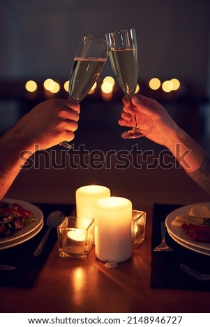 Heres to us and our future. Cropped shot of an unrecognizable couple having a celebratory toast over a candle lit dinner at night.