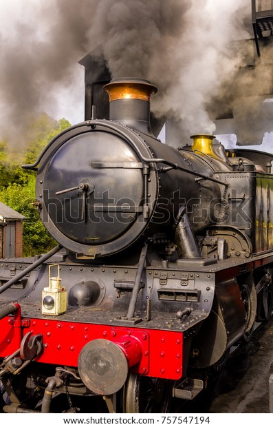 Heritage steam\
engine in steam, waiting under the coal hopper to refill its tender\
on a busy heritage steam\
railway.