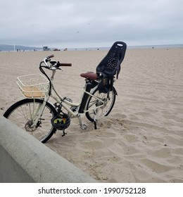 HERMOSA BEACH, CALIFORNIA, June 2021 - White Beach Cruiser Bike With Baby Seat On White Sand Beach 