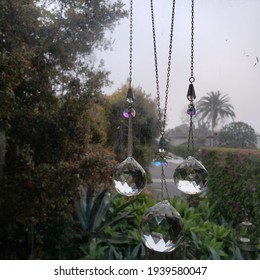 HERMOSA BEACH, CALIFORNIA, March 2021 - Feng Shui Crystals Hanging In A Window With Green Garden In The Background 