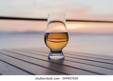 Hero shot of old fashioned whiskey glass on table at sunset seaside