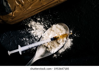 Heroin In A Syringe And Heroin Powder On A Black Background. The Concept Of A Narcotic Substance.