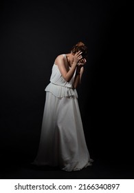 The Heroine Of An Ancient Tragedy In Grief And Loss. A Young Woman In A White Tunic And A Laurel Wreath, An Image In The Ancient Greek Or Roman Style