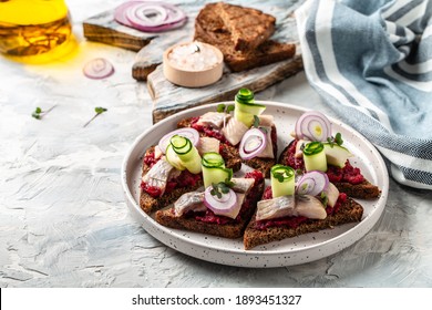 Herring fillet. Scandinavian cuisine. sandwich with slices of pickled Atlantic herring fillet, beetroot salad, green cucumber, onion and microgreen.