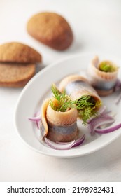 Herring Fillet Twisted In Roll, Onion, Cucumber And Dill In A Plate On The Table. Scandinavian Food.