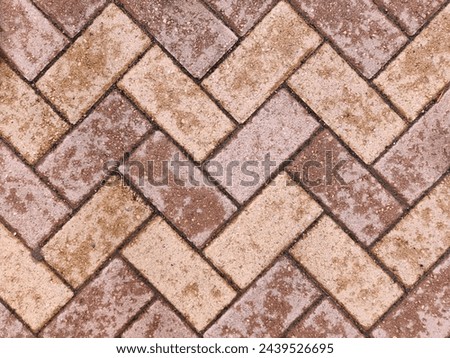 Herringbone brick sidewalk pattern of pavement tiles on rainy day background texture. Wet stret sidewalk pathway surface. Patio pavement.Exterior design element. Geometric diagonal zigzag tile pattern