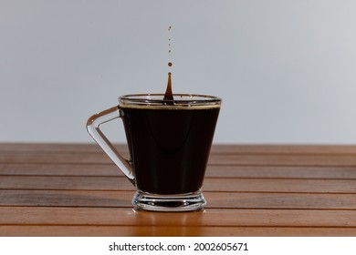 Herselt, Antwerp Belgium - July 5 2021: Reaction Of A Falling Coffee Drop On The Creamy Surface Of Hot Coffee In A Glass Coffee Cup.
