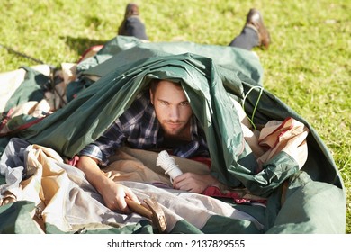 Hes clearly an amateur camper. Frustrated young man struggling to erect a tent outdoors. - Shutterstock ID 2137829555