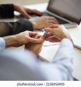 Hes Got Disgusting Manners. A Young Man Clipping His Toenails On His Desk At Work.