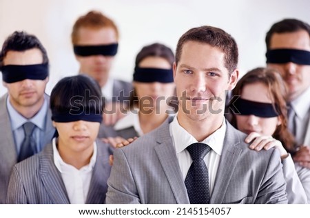 Hes got the knowledge to get ahead of the pack. A young businessman standing in front of a group of blindfolded businesspeople.