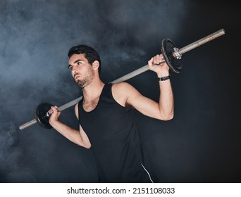 Hes Got No Time For Excuses. Studio Shot Of A Young Man Working Out With A Barbell Against A Gray Background.