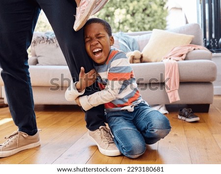 Hes having a bad day. a little boy throwing a tantrum while holding his parents leg at home.