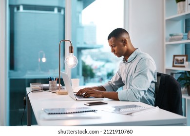 He's In His Productive Zone. Shot Of A Handsome Young Businessman Working On His Laptop During A Late Night Shift At Work.