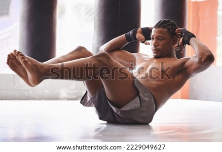 Hes a lean mean fighting machine. Shot of a middle-age boxer working out his abs in a gym.