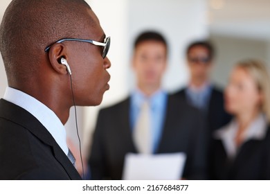 Hes On High Alert. Shot Of A Serious Bodyguard Protecting His Client Who Is Giving A Presentation.