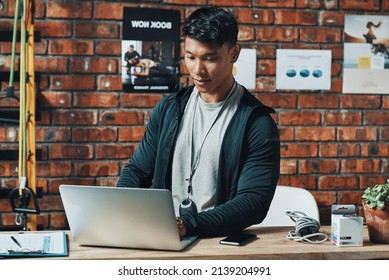 Hes Receiving Even More Subscriptions Online. Cropped Shot Of A Handsome Young Male Fitness Instructor Using A Laptop While Working In A Gym.