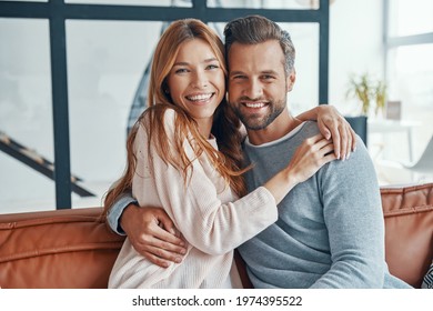 Heterosexual couple smiling and looking at camera while spending time at home