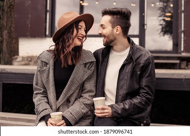 Heterosexual satisfied married couple have a date outside near cafe on pier. Drinking hot chocolate coffee beverage and hugging, kissing, speaking laughing, spend time. Romantic lovers husband wife - Powered by Shutterstock