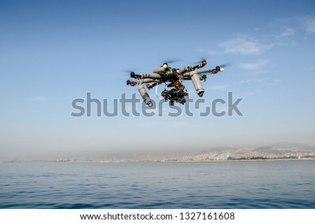 The Hexacopter (Multicopter) drone with the professional camera takes pictures above sea. Uav drone copter flying with digital DSLR camera. High resolution digital camera on the sky.
