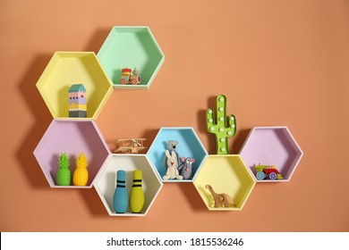 Hexagon shaped shelves with toys on orange wall. Interior design