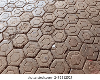 Hexagonal tiles are arranged in a tightly packed pattern, with some sections showing signs of wear and dirt accumulation. The varied shades of brown and subtle irregularities create an interesting vis