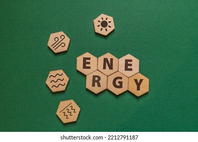 Hexagonal Wooden Plates With The Word Energy And Icons For Solar, Wind, Hydro And Geothermal Energy On A Green Background