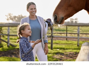 Hey horsey, I got you a snack. an adorable little girl feeding a horse on her farm while her mother looks on. - Powered by Shutterstock