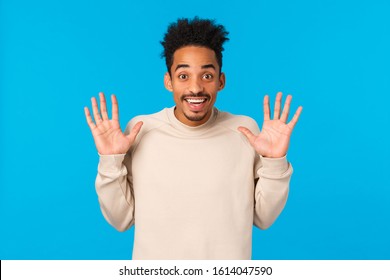 Hey No Hands, I Got Nothing. Cheerful Smiling Handsome African American Boyfriend Fooling Around, Raising Palms In Surrender Gesture, Joking Express Positive Emotions, Winter Concept, Blue Background