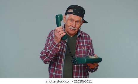 Hey You, Call Me Back. Cheerful Man Secretary In Checked Shirt Talking On Wired Vintage Telephone Of 80s, Asking New Client For Call. Elderly Grandfather Posing Isolated On Gray Studio Wall Background