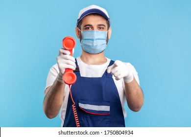 Hey You, Call Me. Handyman In Overalls, Mask, Safety Gloves, Holding Retro Phone Handset And Pointing Finger To Camera. Plumber And Repair Services, Housing Maintenance Help Line. Studio Shot Isolated