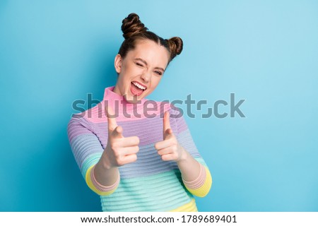 Hey you. Photo of attractive crazy funky lady two buns directing fingers on camera blinking eye flirty person pick select wear casual warm striped sweater isolated blue color background