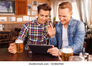 Hey You. Pleasant Cheerful Young Guys Holding Laptop And Making Call In Skype While Drinking Beer.