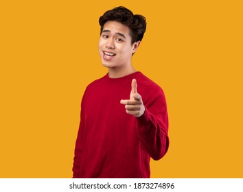 Hey, It's You. Portrait of young asian man in red sweater pointing index finger at camera, posing isolated over orange background wall. Cheerful smiling guy picking, choosing and indicating - Powered by Shutterstock